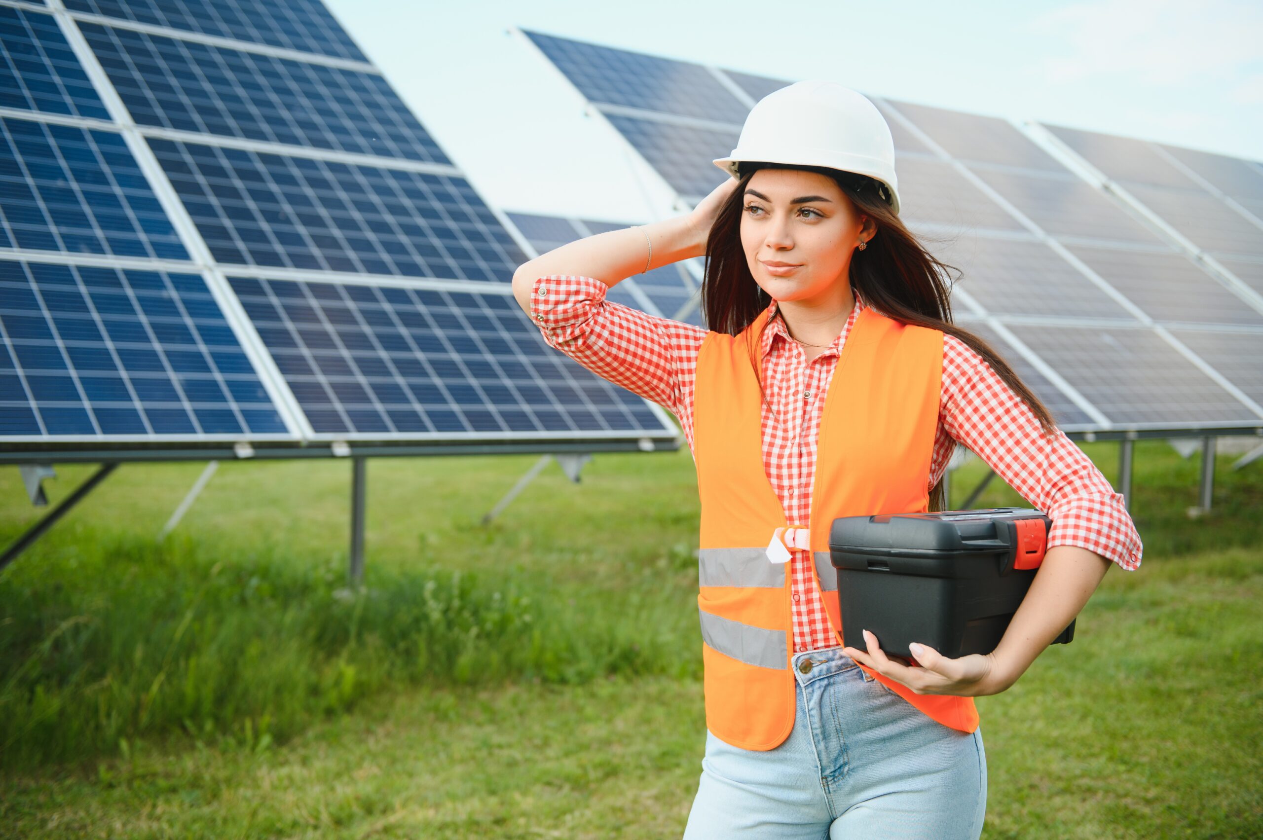 portrait of electrician engineer in safety helmet checking solar panels. female technician at solar station.